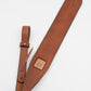 A brown leather rifle sling with a padded center and adjustable straps, featuring stitching details.